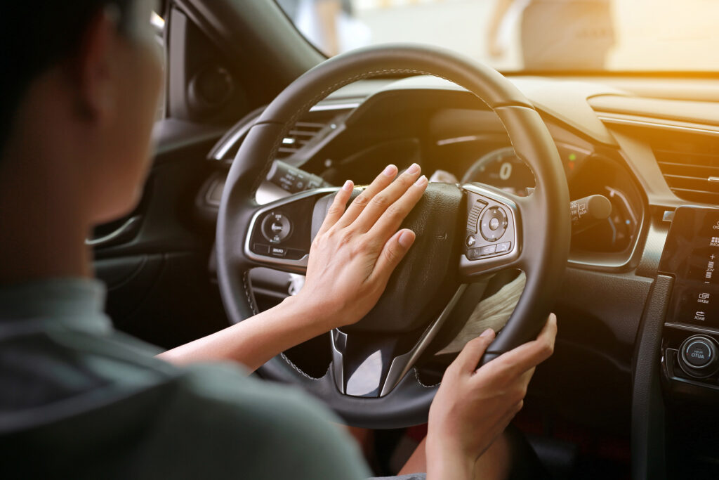 Frau hupt, während sie mit dem Auto die Straße entlangfährt.
