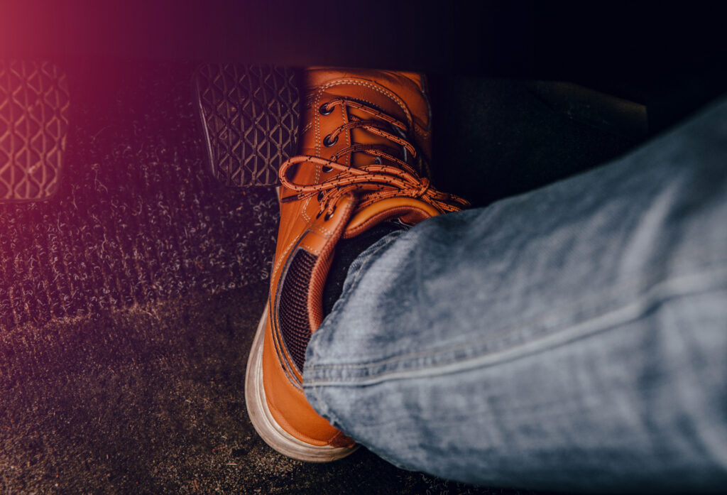 Fuß tritt aufs Gaspedal. Konzept von Beschleunigung, rücksichtlosem Fahren, Geschwindigkeitsüberschreitung und Bußgeldern.